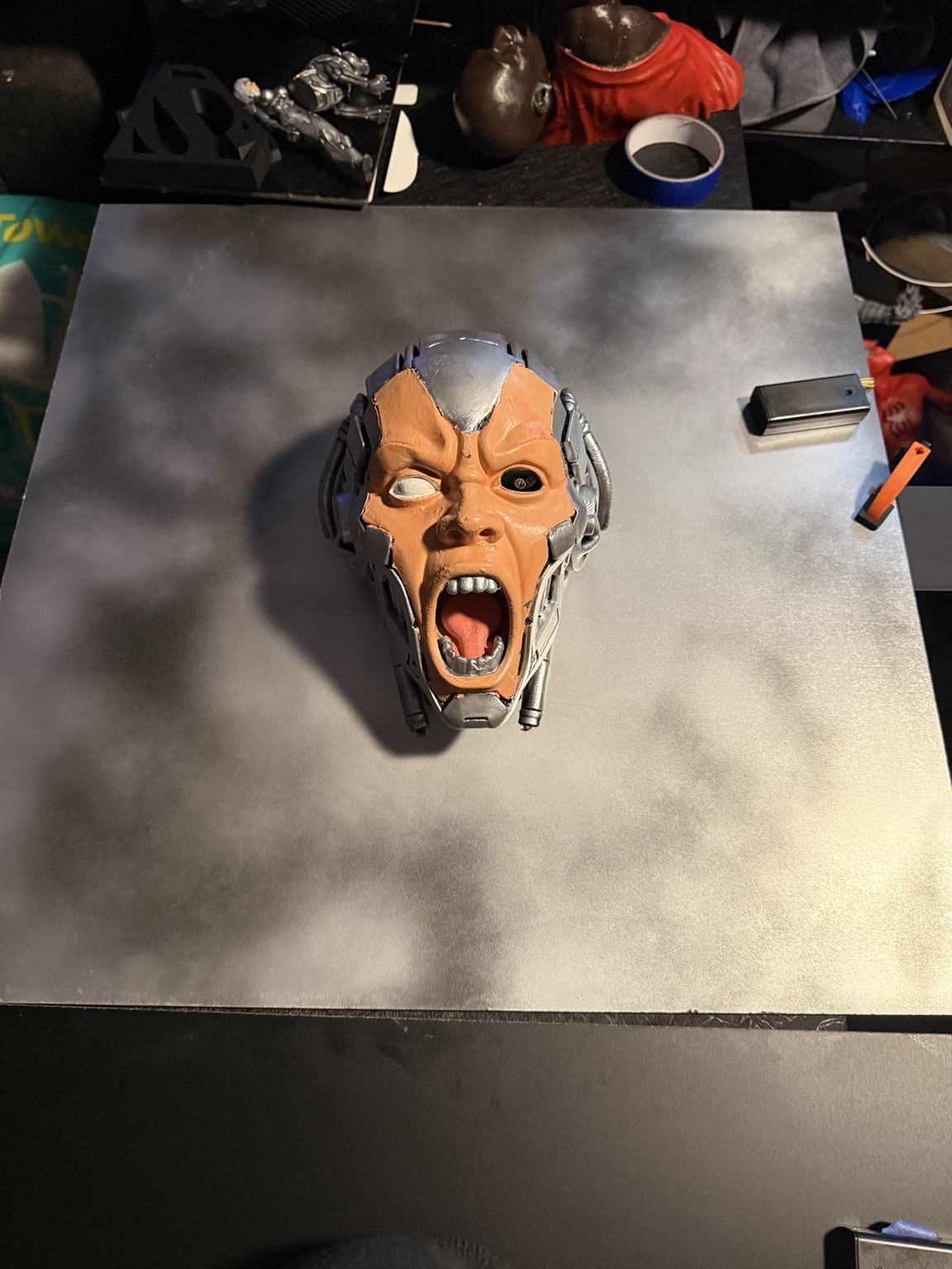 Cybernetic sculptural head mounted on a smoky metallic canvas